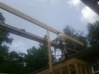 Carpenter setting a ridge beam over a new addition frame — Ice Dam Removal by Roofing Brothers in Phillips