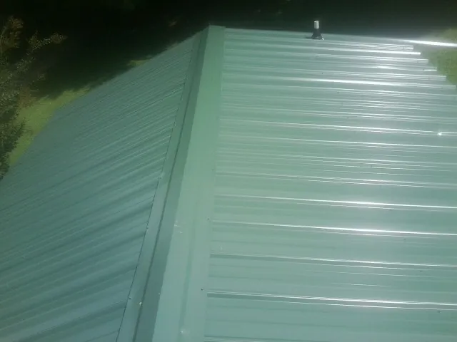 New green metal panels meeting at the ridge of a roof — Flat Roof Repair work by our crew in Phillips