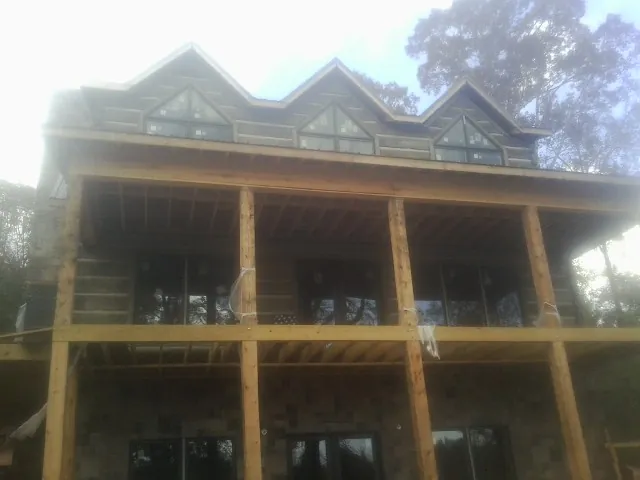 Dormers and porch framing on a large log home under construction — Roof Coating work by our crew in Phillips