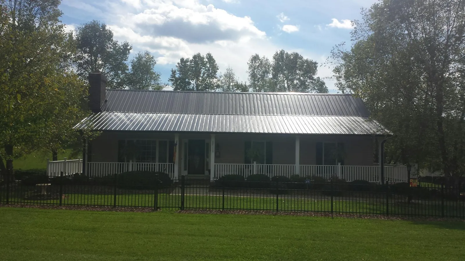 Gray metal roof on a brick ranch with a full width front porch — Gutter Guard Installation work by our crew in Phillips