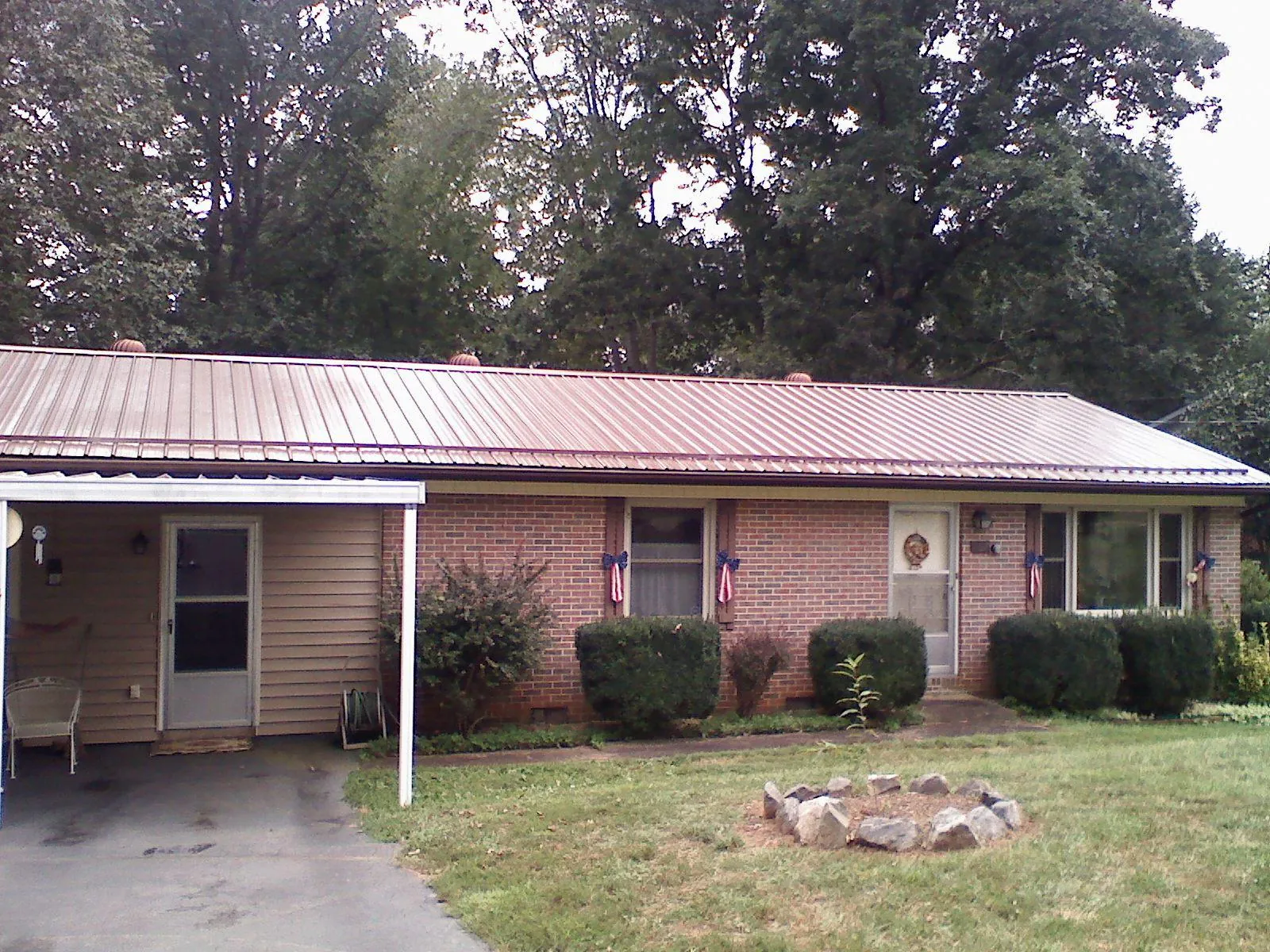 Bronze metal roof and carport on a brick ranch home — Roof Repair work by our crew in Phillips