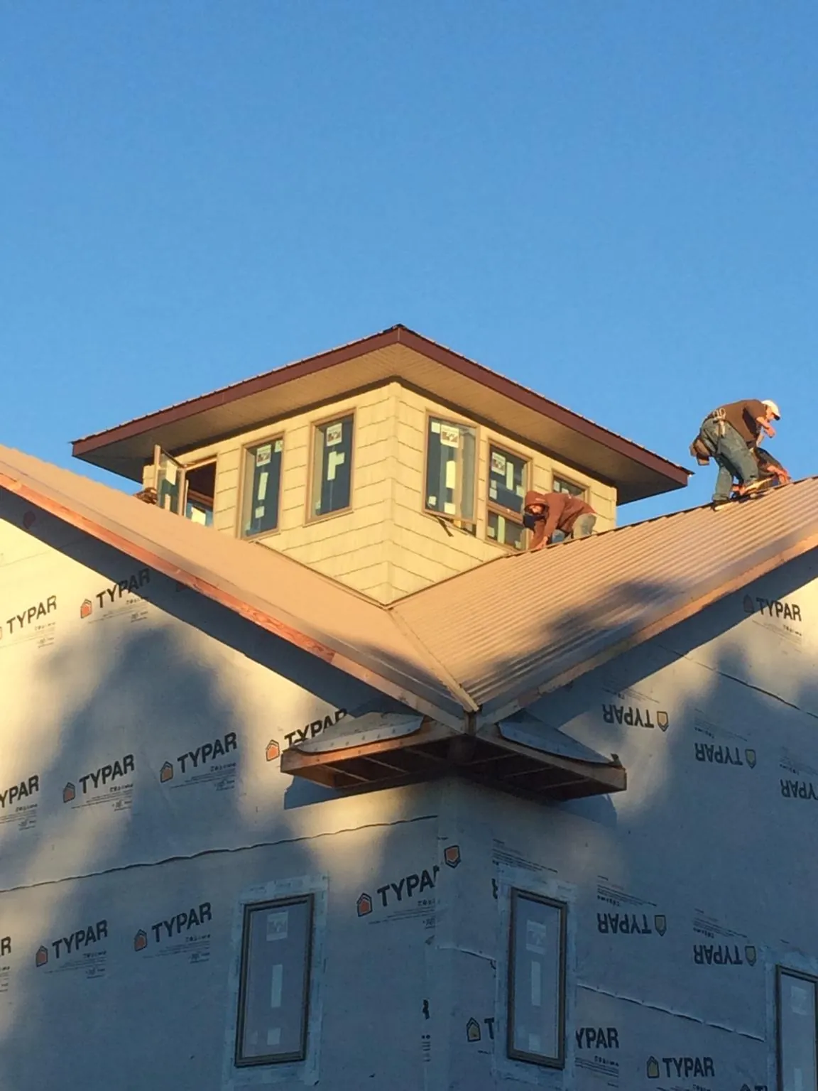 Roofers working around a rooftop cupola on a new metal roof at sunset — Roof Waterproofing in Phillips by Roofing Brothers